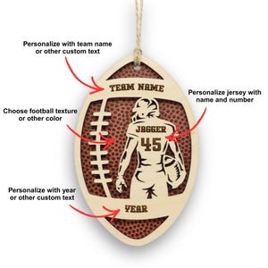 May include: A wooden football-shaped ornament with a football texture background. The ornament features a football player silhouette with the name "JAGGER" and the number "45". The text "TEAM NAME" and "YEAR" are at the top and bottom, respectively. Includes a string for hanging.