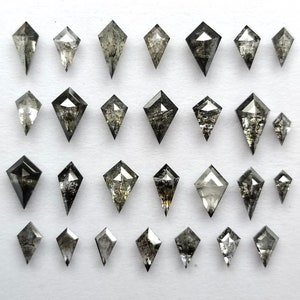 May include: A collection of 27 black and grey kite-shaped diamonds, arranged in rows on a white surface.