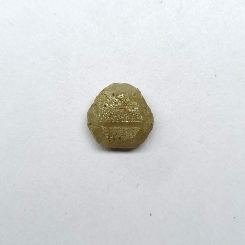 Pu&ograve; includere: Una pietra preziosa grezza, sfaccettata, di colore verde chiaro, di forma esagonale.