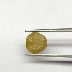 Pu&ograve; includere: Un diamante grezzo giallo sfaccettato tenuto in una pinza. Il diamante &egrave; una pietra naturale non levigata.
