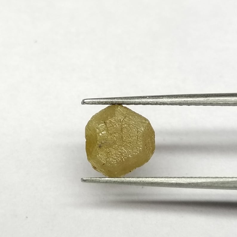Pu&ograve; includere: Un diamante grezzo giallo sfaccettato tenuto in una pinza. Il diamante &egrave; una pietra naturale non levigata.