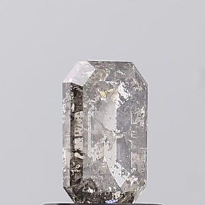 May include: A rectangular-cut gemstone with a grey and clear appearance. The gem has a textured surface and multiple facets, reflecting light. The gemstone is set against a plain, light background.
