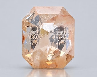 May include: An emerald-cut sunstone gemstone featuring a translucent peach and orange hue with internal metallic copper-coloured inclusions that create a shimmering, reflective effect throughout the faceted surface of the stone.
