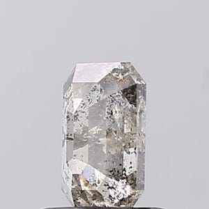 May include: A clear, grey rectangular-cut gemstone with internal inclusions. The gem has a polished surface with multiple facets, reflecting light. The overall shape is a tall, rectangular prism, showcasing the stone's clarity and unique characteristics.