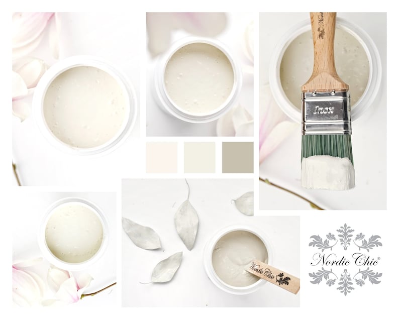 May include: A close-up of a white paint in a jar with a brush and a wooden stick. The paint is in a white jar with a black label that says "Nordic Chic". The paint is surrounded by white flowers and leaves.