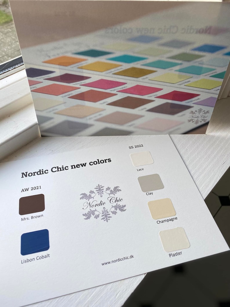 May include: A color chart with paint swatches for the brand Nordic Chic. The chart shows new colors for the Spring/Summer 2022 and Autumn/Winter 2021 seasons. The colors include Lace, Clay, Champagne, Plaster, Mrs. Brown, and Lisbon Cobalt.