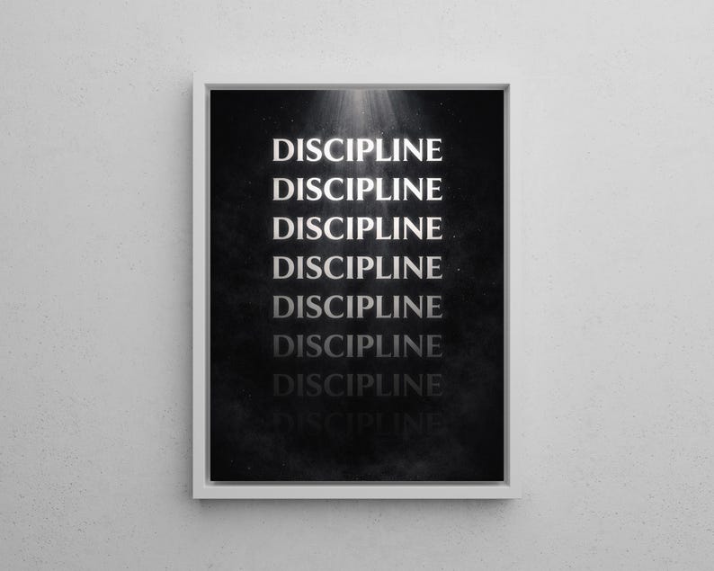 May include: A framed print with the word "DISCIPLINE" repeated vertically in a white, bold font against a dark, textured background. The print is in a white frame and is mounted on a white wall.