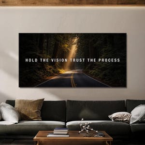 May include: A canvas print featuring a road winding through a lush forest, with sunlight streaming through the trees. The text "HOLD THE VISION TRUST THE PROCESS" is displayed in white across the top of the image.