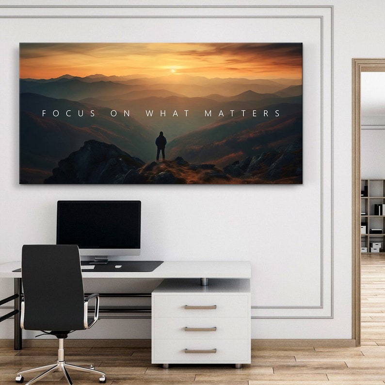 May include: A motivational quote, "FOCUS ON WHAT MATTERS", is displayed on a canvas print featuring a silhouette of a person standing on a mountaintop overlooking a misty valley at sunset.
