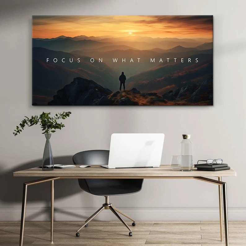 May include: A motivational canvas print with a silhouette of a person standing on a mountaintop overlooking a vast landscape with a sunset in the background. The text "FOCUS ON WHAT MATTERS" is printed in white on the canvas.