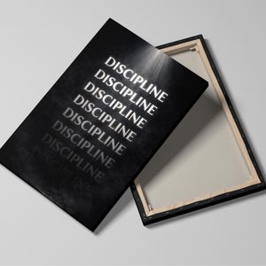 May include: A black canvas print with the word "DISCIPLINE" repeated in white, angled against a white background. The canvas is stretched over a wooden frame, with the back of the canvas visible.