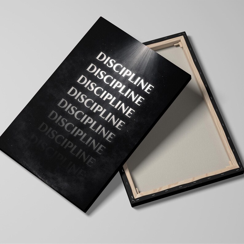May include: A black canvas print with the word "DISCIPLINE" repeated in white, angled against a white background. The canvas is stretched over a wooden frame, with the back of the canvas visible.