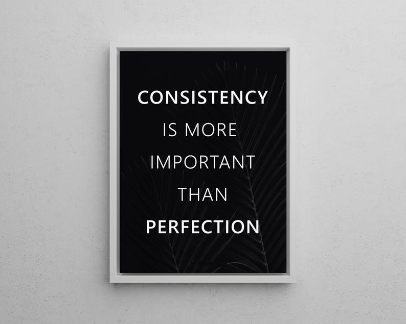 K&ouml;nnte beinhalten: Gerahmter Druck mit dem Text "CONSISTENCY IS MORE IMPORTANT THAN PERFECTION" in Wei&szlig; auf schwarzem Hintergrund. Der Druck hat einen wei&szlig;en Rand und ein subtiles Palmenblatt-Design.
