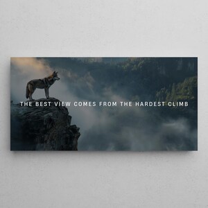 Może przedstawiać: Wilk stoi na skalistej klifie z widokiem na mglistą dolinę. Pod wilkiem widnieje napis "THE BEST VIEW COMES FROM THE HARDEST CLIMB".