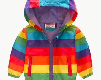 May include: A colorful rainbow striped jacket with a purple hood and zipper closure. The jacket has a label that says "JOMAK" on it.