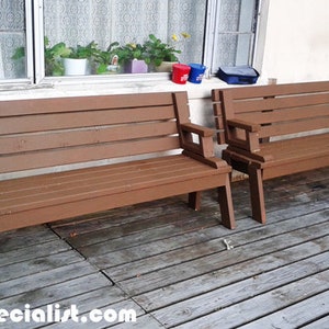 Pu&ograve; includere: Due panche in legno marrone con braccioli su un terrazzo in legno. Le panche hanno un design a doghe e sono dipinte in un caldo colore marrone. Lo sfondo comprende una finestra con piante e un muro bianco.