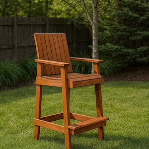 May include: A high wooden bar stool with a natural finish. The stool has a slatted back, armrests, and a footrest. It is positioned on a grassy lawn with trees in the background, suitable for outdoor use.