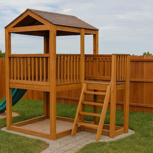 Pode incluir: Conjunto de jogos de madeira com telhado castanho, escorrega azul e escada de madeira. O conjunto de jogos está situado num relvado verde com uma vedação de madeira ao fundo. O conjunto de jogos tem uma área de caixa de areia.