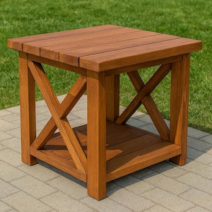 May include: A square wooden side table with a natural finish. The table features an X-shaped design on the sides and a slatted top. The table measures approximately 24 inches in height and width.
