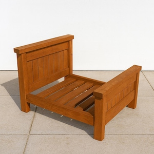 May include: A small, wooden pet bed with a warm, reddish-brown finish. The bed has a headboard and footboard with vertical slats, and a slatted base. The bed is approximately 24 inches long and 18 inches wide.