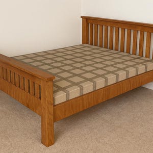 May include: A wooden bed frame with a headboard and footboard. The bed frame is made of light brown wood and has a grid-patterned mattress. The headboard and footboard have vertical slats.