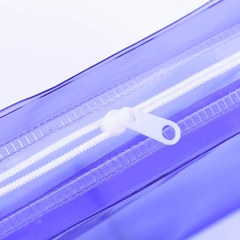 May include: Close-up of a clear purple zippered pouch with a white zipper pull.