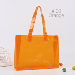 May include: A clear orange tote bag with two handles. The bag is made of a transparent plastic material and has a bright orange color. The text #20 Orange is visible in the top right corner of the image.