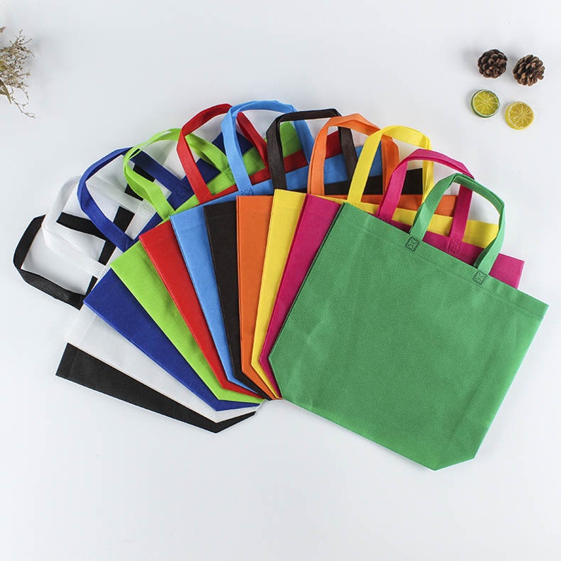 May include: A collection of 14 reusable shopping bags in various colors, including white, black, green, blue, red, orange, and yellow. The bags are made of non-woven fabric and have a simple design with two handles.