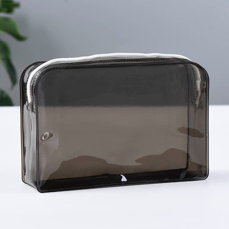 May include: A clear, semi-transparent black zippered pouch with a white zipper pull.