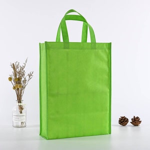 May include: A bright green reusable shopping bag with two handles. The bag is made of non-woven fabric and is a great alternative to plastic bags.