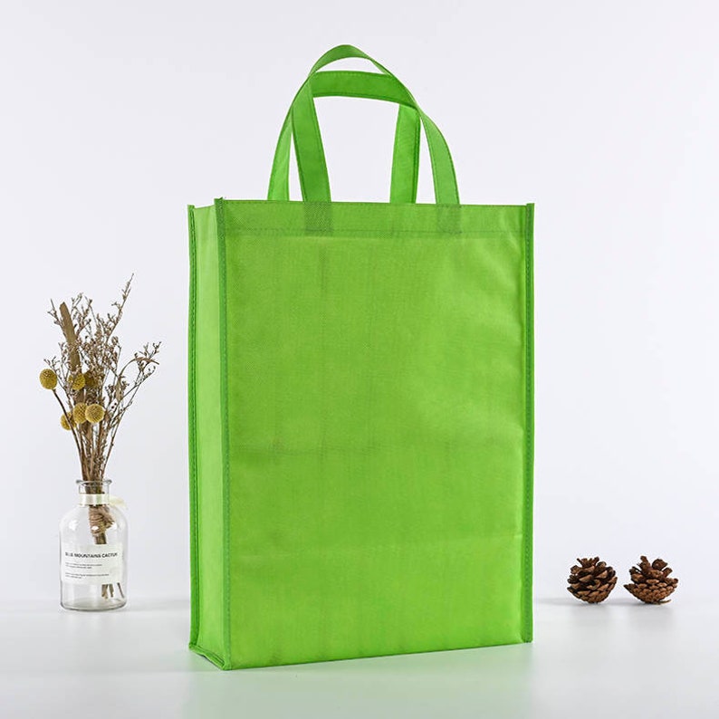 May include: A bright green reusable shopping bag with two handles. The bag is made of non-woven fabric and is a great alternative to plastic bags.