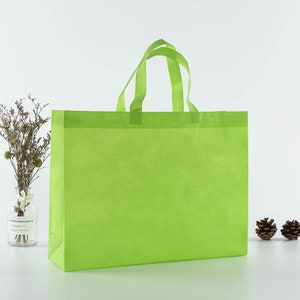 May include: A bright green reusable shopping bag with two handles. The bag is made of non-woven fabric and is a great alternative to plastic bags.