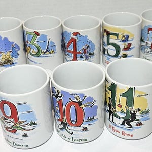 May include: Set of 12 white ceramic mugs with colorful illustrations and numbers 1 through 12. Each mug features a different Christmas-themed scene with a corresponding number.