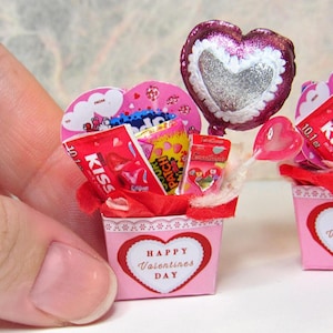 May include: A pink and red Valentine's Day gift basket filled with candy, a heart-shaped balloon, and a lollipop. The basket is decorated with a white lace trim and a heart-shaped label that says "Happy Valentine's Day".