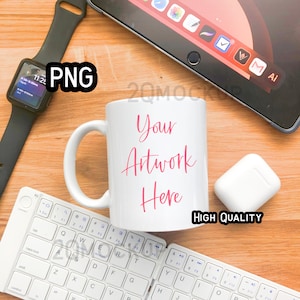 May include: White ceramic mug with a pink inscription that reads "Your Artwork Here". The mug is on a wooden surface with a white keyboard, a black smartwatch, and a white case for wireless earbuds.
