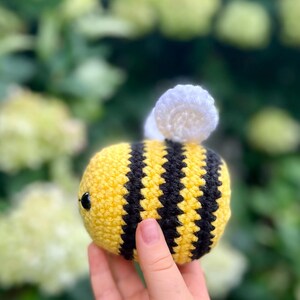 K&ouml;nnte beinhalten: Ein geh&auml;keltes Bienentier mit gelben und schwarzen Streifen und wei&szlig;en Fl&uuml;geln. Die Biene wird in einer Hand gehalten.