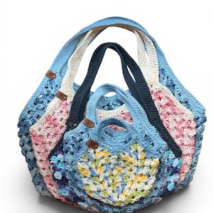 May include: A set of three nested crochet tote bags featuring a granny square pattern in various colors including light blue, pink, white, yellow, and dark blue. Each bag has two handles and a small brown leather-like tag attached to the side.