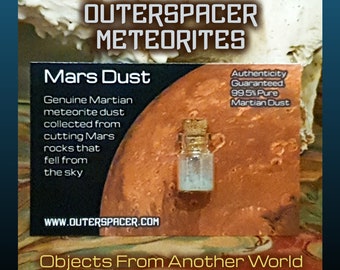 May include: A small glass bottle with a cork stopper containing a sample of Martian meteorite dust. The bottle is labeled "Mars Dust" and "Authenticity Guaranteed 99.5% Pure Martian Dust". The label also includes the website address "www.outerspace.com" and the text "Objects From Another World".