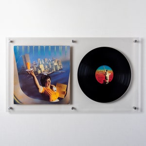 May include: A framed vinyl record and album cover. The album cover features a woman in a diner uniform holding a drink, with the band name "Supertramp" at the top. The vinyl record is black with a colorful label.