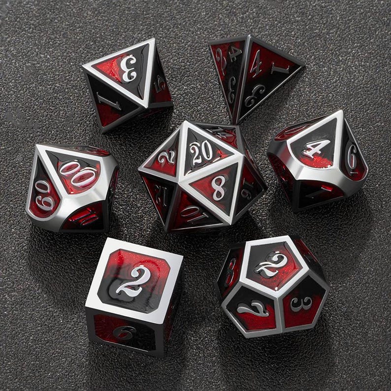 May include: A set of seven polyhedral dice for tabletop games. The dice are silver with black and red accents. Each die has white numbers. The dice are arranged on a dark gray surface.