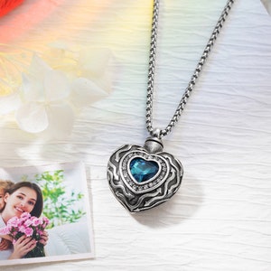 May include: Silver heart-shaped pendant necklace with a blue crystal and clear rhinestones. The pendant is on a silver chain.