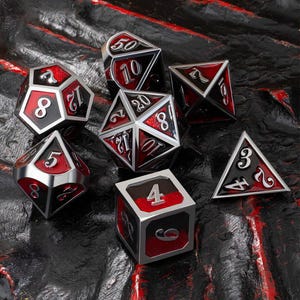 May include: A set of seven polyhedral dice in a variety of shapes. The dice are black with red faces and silver trim. Numbers are displayed in a white, stylized font. The dice are for tabletop gaming.