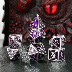 May include: Set of six silver and purple metal dice with numbers 1 through 6. The dice are in a pyramid shape with the top die showing a 5.