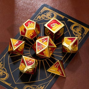 May include: A set of seven polyhedral dice in gold, red, and yellow. The dice are arranged on a black card with a gold dragon design. The dice are for role-playing games.