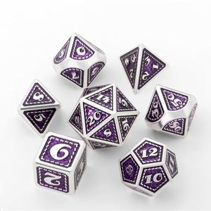 May include: Set of seven silver and purple polyhedral dice with a stitched design. The dice are numbered 1-20, 4, 6, 8, 10, 12.