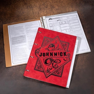 Puede incluir: Un archivador de cuero rojo con un diseño en blanco y negro que presenta un dragón y el texto "JOHN WICK".