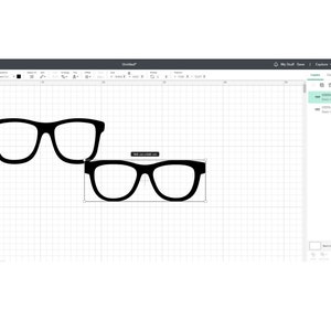 May include: Two pairs of black eyeglasses, one pair is slightly larger than the other. The eyeglasses are on a white grid background.