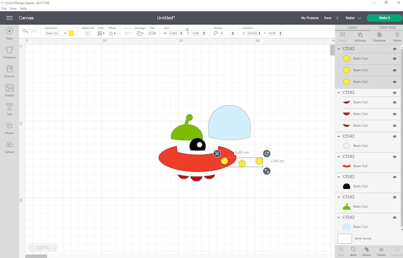 May include: A red, green, yellow and white UFO design with three yellow circles on the bottom. The design is on a white grid background.