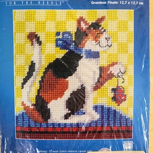 May include: A needlepoint kit featuring a calico cat playing with a red and blue toy mouse. The kit includes 12-mesh cotton interlock canvas, wool yarn, a graph, and instructions. The finished size is 5 inches by 5 inches.