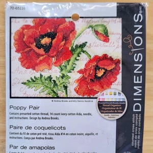 May include: A Dimensions counted cross stitch kit featuring a Poppy Pair design. The kit includes pre-sorted cotton thread, 14 count ivory cotton Aida, a needle, and instructions. The package measures 7 inches by 5 inches (17 cm x 12 cm).